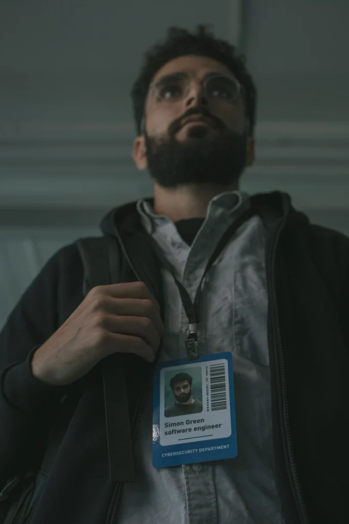 Un homme avec un badge d'accès bleu est accroché autour de son cou, indiquant « software engineer » et « CYBERSECURITY DEPARTMENT ».
