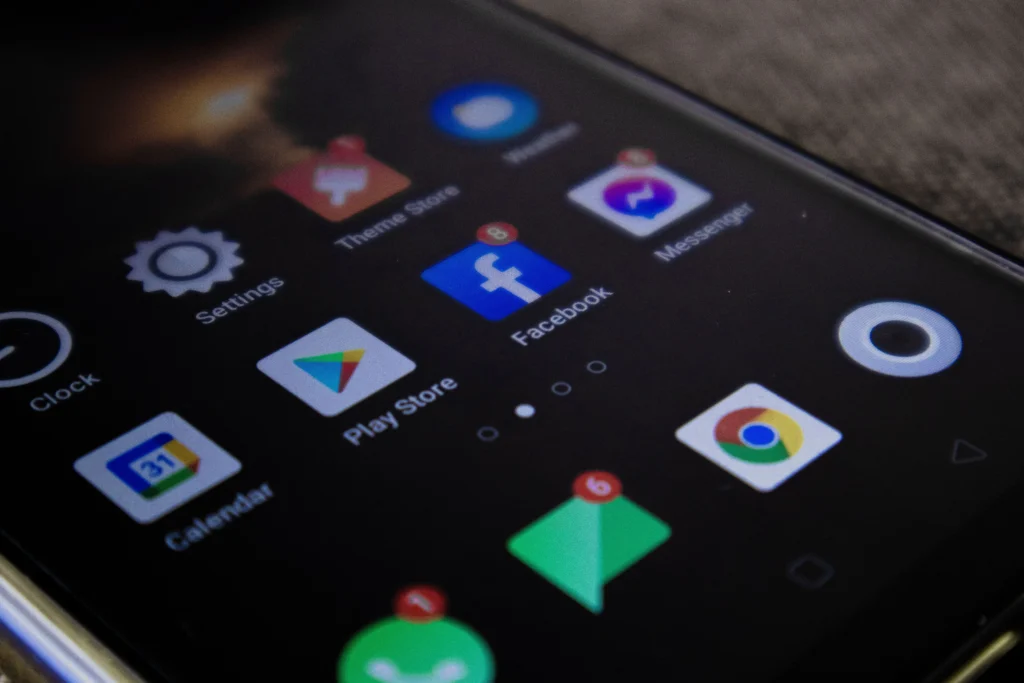 Vue rapprochée et en angle de l'écran d'un smartphone affichant plusieurs icônes d'applications.