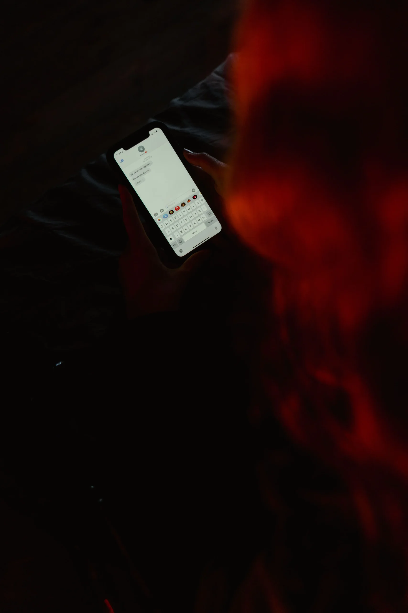 Vue plongeante d'une personne tenant un smartphone, dont l'écran affiche une interface de messagerie.