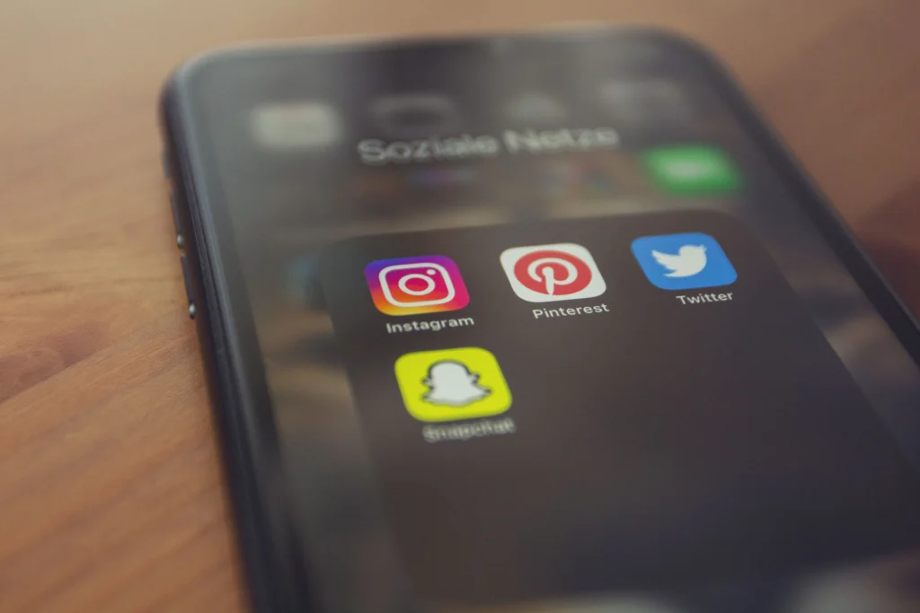 Plan rapproché sur un smartphone posé sur une table. L'écran affiche un dossier contenant des Réseaux sociaux.