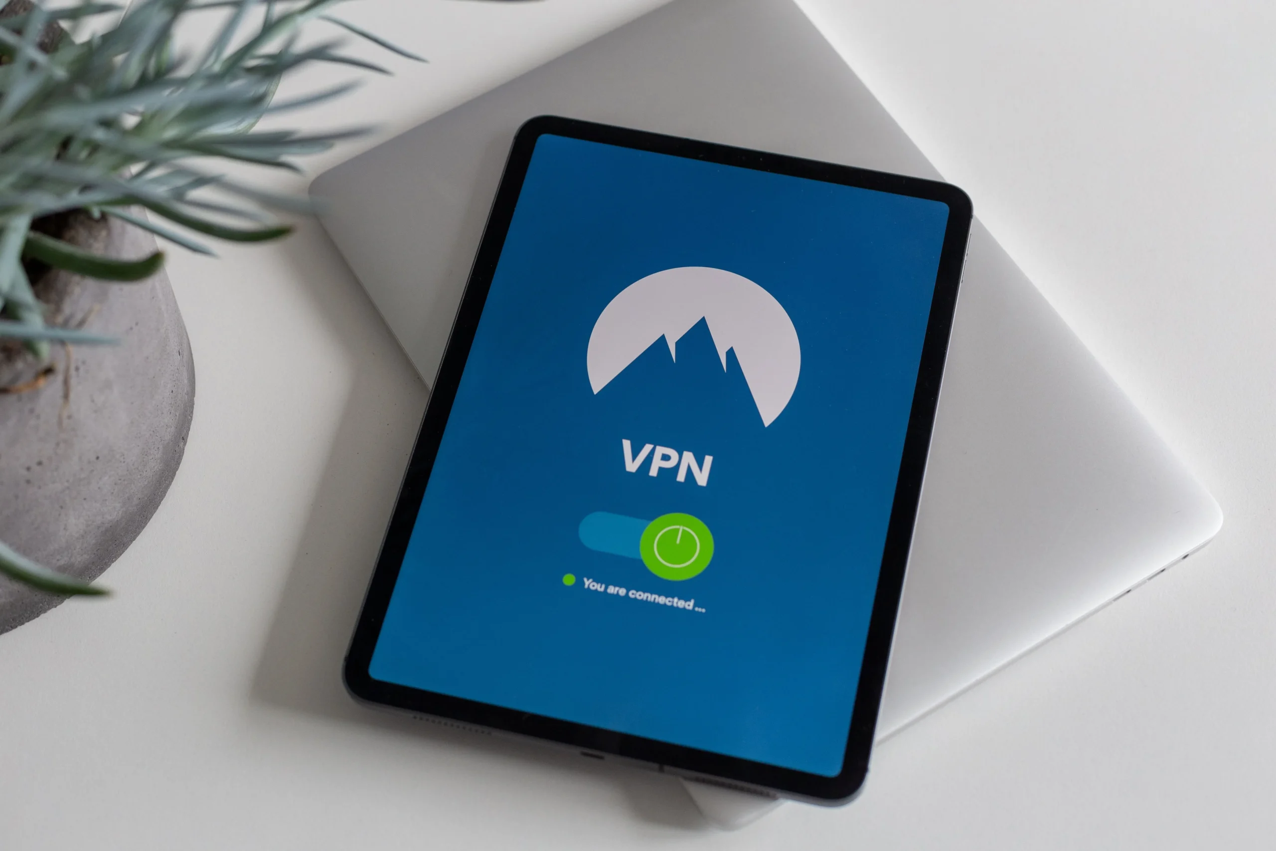 Vue du dessus d'une tablette. L'écran de la tablette affiche l'interface d'une application VPN activé.
