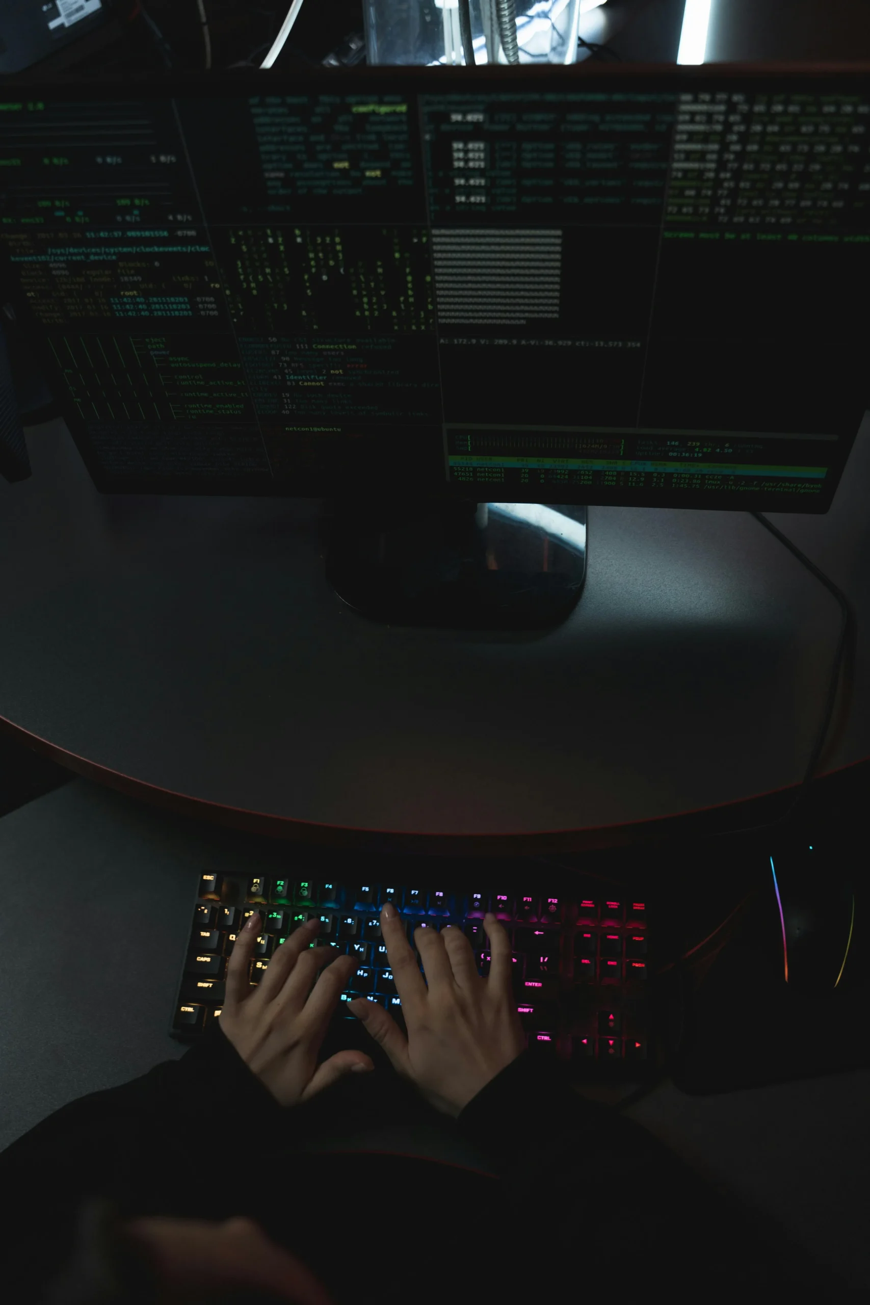 Vue du dessus d'une personne tapant sur un clavier face à un écran affichant des terminaux.