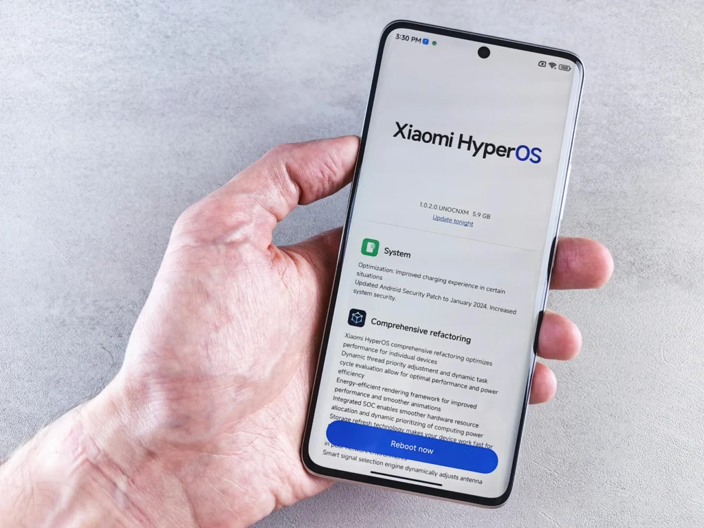 Vue du dessus d'une main tenant un smartphone. L'écran affiche une interface de mise à jour système.